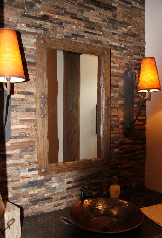 Rustic bathroom remodel with stacked stone wall, copper vessel sink, and warm sconce lighting — Tincher's Custom Homes