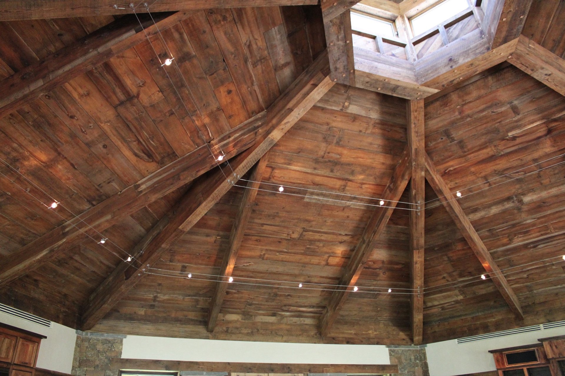 Reclaimed timber beam cathedral ceiling with skylight and string lights in a metal building custom home — Tincher's Custom Homes