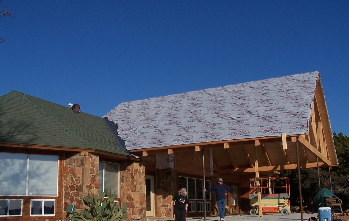 Home addition construction showing timber frame and cedar siding attached to existing stone home — Tincher's Custom Homes