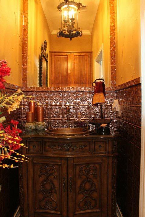 Ornate powder room remodel with antique copper vessel sink, hand-carved wood vanity, and pressed tin tile — Tincher's Custom Homes