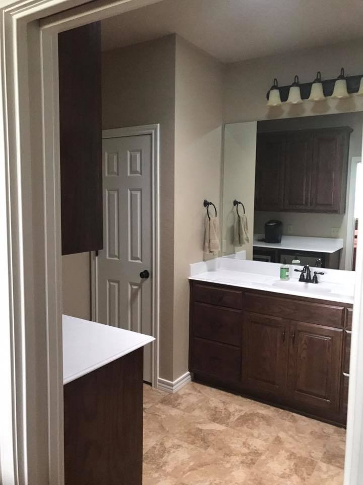 Custom bathroom remodel with dark wood vanity, white quartz countertop, large mirror, and warm vanity lighting — Tincher's Custom Homes