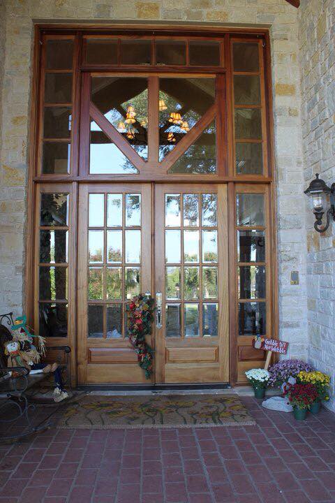 Grand wood French double door entry with full-height transom windows set in limestone home — Tincher's Custom Homes